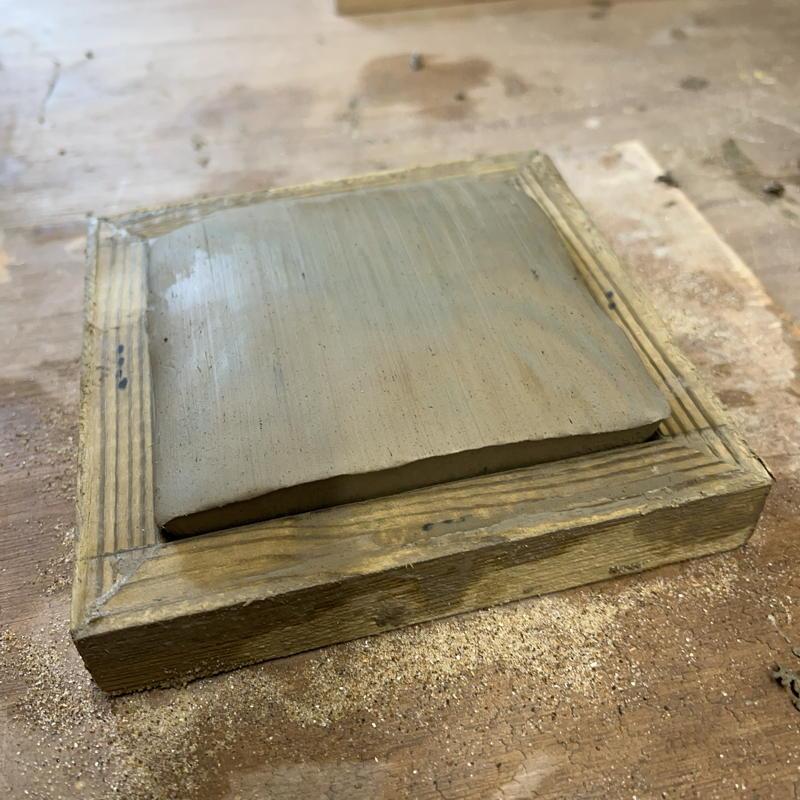 distorted tile being pushed from bevelled mould