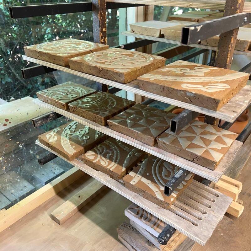 Tiles with white slip added drying on rack